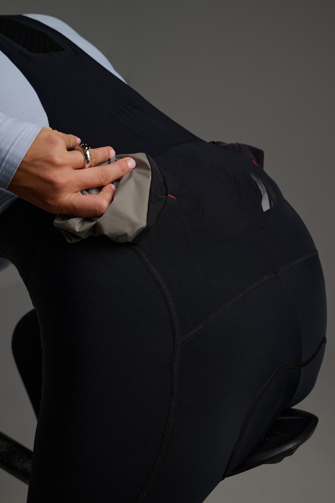 Bolsillo trasero de malla transversal para transportar chaquetas, chalecos u otros objetos de forma accesible.